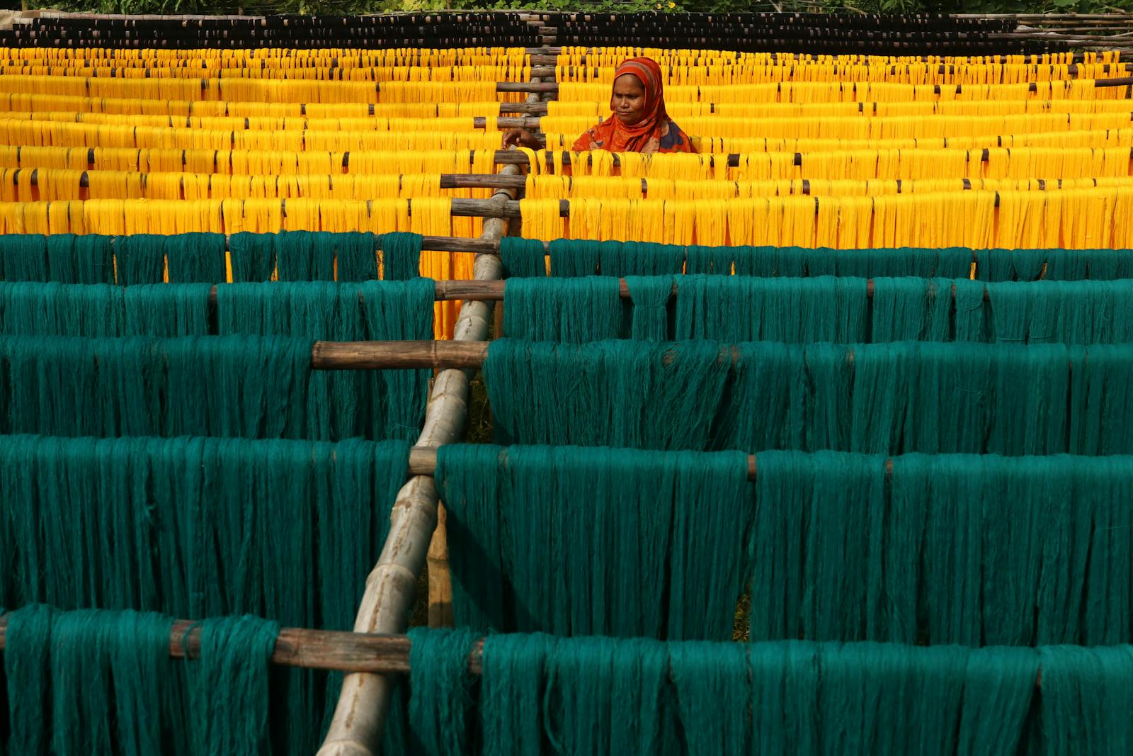 A woman works among colorful textile drying racks in Narayanganj, Bangladesh.